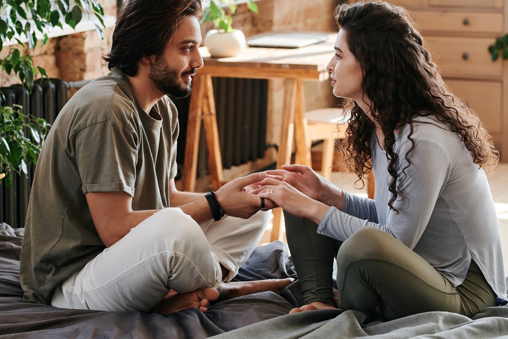 couple talking and listening on a bed